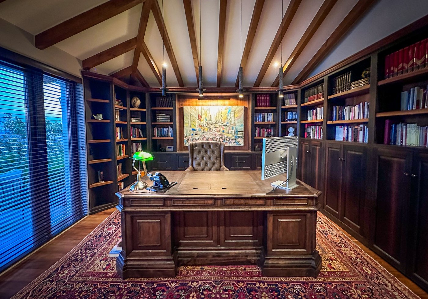 Biblioteca y oficina con techo de vigas y libreros de madera