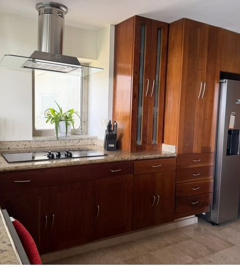 Cocina con isla, campana de acero y gabinetes de madera